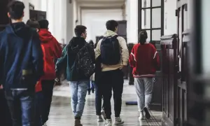 Młodzież w szkolnym korytarzu, plecaki na plecach, jakby właśnie kiedy składa się papiery do liceum.
