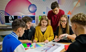 Młodzi ludzie, przyszli **technicy reklamy**, analizują palety kolorów i projekty.