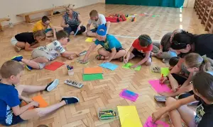 Dzieci klas 1-3 biorą udział w zabawach integracyjnych, rysując na kolorowych kartkach.