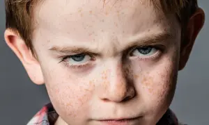 Zmarszczone brwi i spojrzenie chłopca z piegami sugerują problemy z zachowaniem.