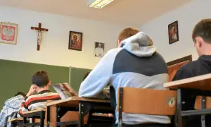 Uczniowie siedzą w klasie z portretem papieża i krzyżem na ścianie. Czy religia wlicza się do średniej?