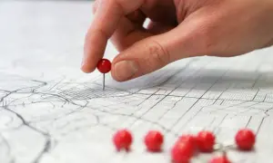 Dłoń z czerwonym pinezką na mapie miasta, ilustrującej różne rodzaje map i ich zastosowania.