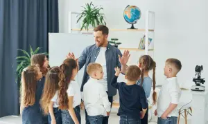 Nauczyciel z uśmiechem daje piątki dzieciom, jakby właśnie skończył się rok szkolny i nadszedł czas, kiedy jest wystawienie ocen.