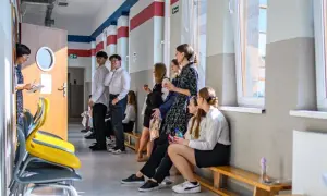 Uczniowie czekają na korytarzu szkolnym, być może na zwolnienie z egzaminu ósmoklasisty.
