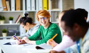 Uśmiechnięty rudowłosy student cieszy się z możliwości nauki. Szkoła policealna online za darmo otwiera drzwi do wiedzy dla każdego.