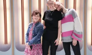 Osoba niebinarna co to znaczy? Trzy uśmiechnięte osoby stoją razem, jedna z nich ma krótkie włosy i okulary, druga z brodą i w swetrze w paski, a trzecia w sukience i jeansowej kurtce.