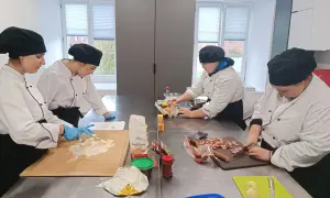 Uczniowie na kierunku technik żywienia i usług gastronomicznych ćwiczą krojenie kiełbasy i przygotowanie ciasta.