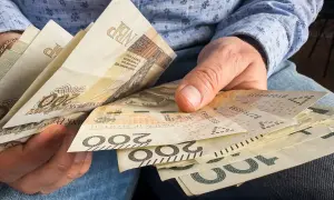 Dłonie trzymają polskie banknoty 200 zł i 100 zł. Zastanawiasz się, czy 800 plus wlicza się do dochodu?