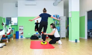 Fizjoterapeutka pomaga pacjentce ćwiczyć równowagę na dysku balansującym, rozwijając czucie głębokie.