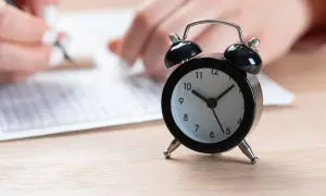 Budzik obok arkusza egzaminacyjnego. Czas na egzamin ósmoklasisty tyka nieubłaganie.