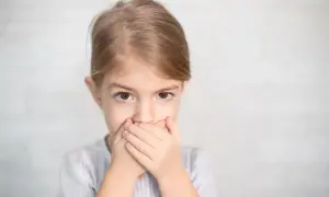 Dziewczynka zakrywa usta dłońmi, jakby nie mogła nic powiedzieć. Czy to afazja? Co to jest?