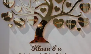 Złote serca z imionami uczniów na tle drzewa, pod napisem "Klasa 8 a".