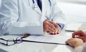 Lekarz w białym kitlu pisze coś na dokumentach. Czy na badania okresowe należy się dzień wolny?
