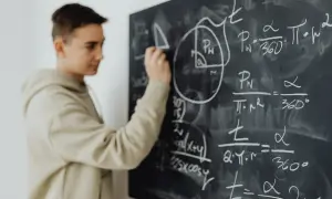 Chłopak rozwiązuje zadania z matematyki na tablicy. W 4 klasie liceum przedmioty takie jak matematyka stają się kluczowe.