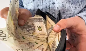 Ręce trzymają portfel z banknotami 200 zł. To nagroda jubileuszowa za 15 lat pracy, symbol docenienia za lata zaangażowania.