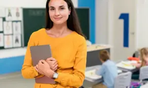 Nauczycielka z tabletem w klasie, przygotowująca się do zajęć, które mogą być częścią studiów podyplomowych nauczyciel wspomagający.