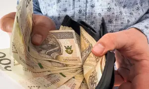 Ręce trzymają portfel z banknotami 200 zł. To symbol nagrody jubileuszowej za 40 lat pracy w budżetówce.