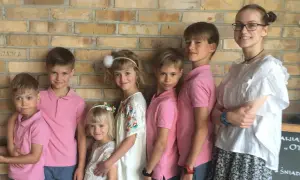 Szczęśliwa rodzina wielodzietna pozuje do zdjęcia na tle ceglanej ściany.