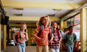 Radosne dzieci biegną szkolnym korytarzem z plecakami. Czy wielki czwartek jest wolny od szkoły? Pewnie tak, skoro tak się cieszą!