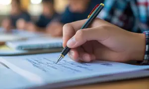 Dłoń pisze długopisem w zeszycie, przygotowując się do poprawki w sierpniu.