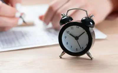 Budzik obok arkusza egzaminacyjnego. Czas na rozwiązanie zadań z matematyki ósmoklasisty mija.