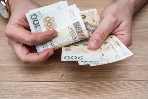 Ręce liczą banknoty 100 i 200 zł. To pieniądze na wymarzone wczasy pod gruszą, by odpocząć od codzienności.