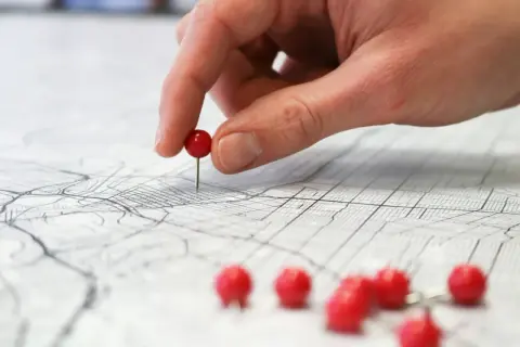Dłoń z czerwonym pinezką na mapie miasta, ilustrującej różne rodzaje map i ich zastosowania.