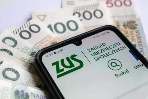 Telefon z aplikacją ZUS na tle polskich banknotów. Sprawdź, czy zasiłek dla bezrobotnych wlicza się do emerytury.