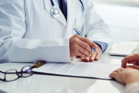 Lekarz w białym kitlu pisze coś na dokumentach. Czy na badania okresowe należy się dzień wolny?
