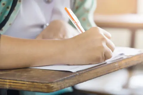 Uczeń pisze na kartkówce, zdobywając wiedzę z zakresu edukacji zdrowotnej.