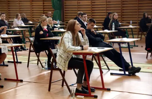 Uczniowie siedzą w ławkach podczas egzaminu, rozpoczynając nowy rok szkolny.