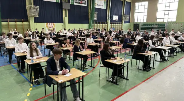 Uczniowie w ławkach podczas egzaminu 8 klasisty 2026. Skupieni, czekają na rozpoczęcie.