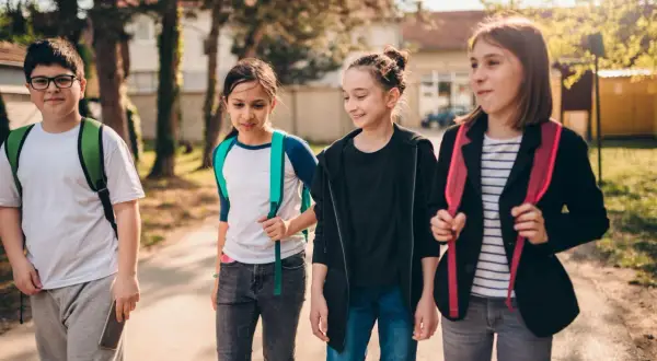 Grupa dzieci idzie razem, może planując wagary. Mają plecaki i wyglądają na podekscytowanych.