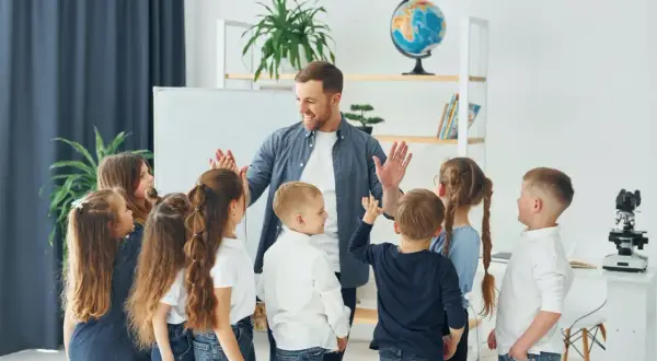 Nauczyciel z uśmiechem daje piątki dzieciom, jakby właśnie skończył się rok szkolny i nadszedł czas, kiedy jest wystawienie ocen.