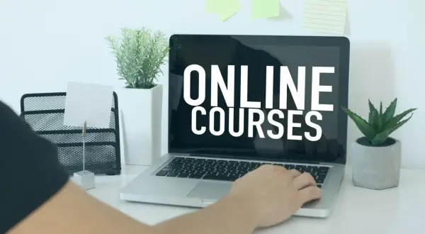 Osoba korzysta z laptopa z napisem "ONLINE COURSES". To idealne miejsce do rozpoczęcia kursu rejestratorka medyczna online.