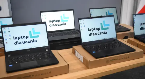 Kilka laptopów z logo "laptop dla ucznia" na ekranach, gotowych do przekazania uczniom.