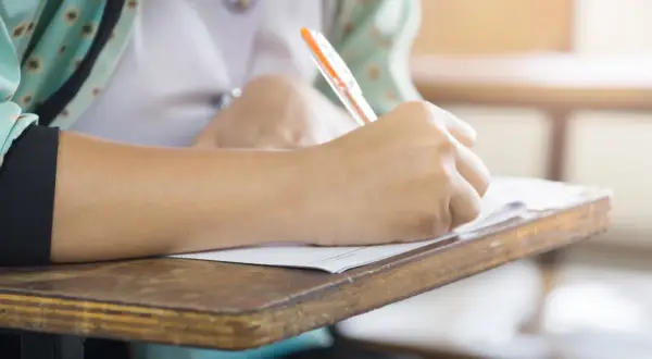 Uczeń pisze na kartkówce, zdobywając wiedzę z zakresu edukacji zdrowotnej.