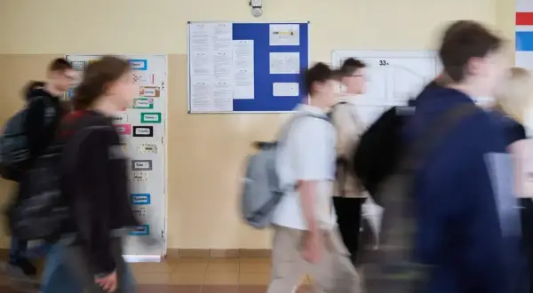Uczniowie spieszą się korytarzem szkolnym, gdzie wiszą ogłoszenia. Może to być ważna informacja od minister edukacji narodowej.