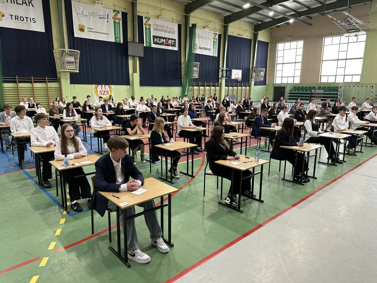 Uczniowie w ławkach podczas egzaminu 8 klasisty 2026. Skupieni, czekają na rozpoczęcie.