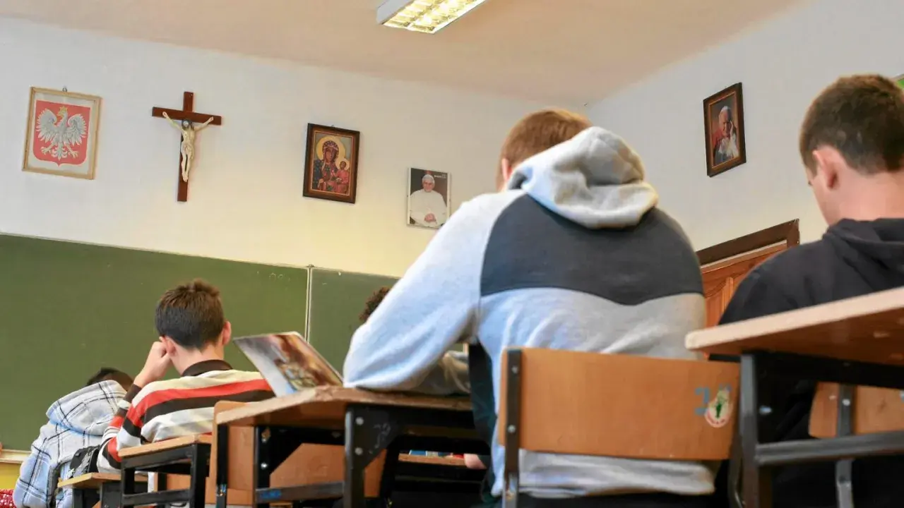 Uczniowie siedzą w klasie z portretem papieża i krzyżem na ścianie. Czy religia wlicza się do średniej?