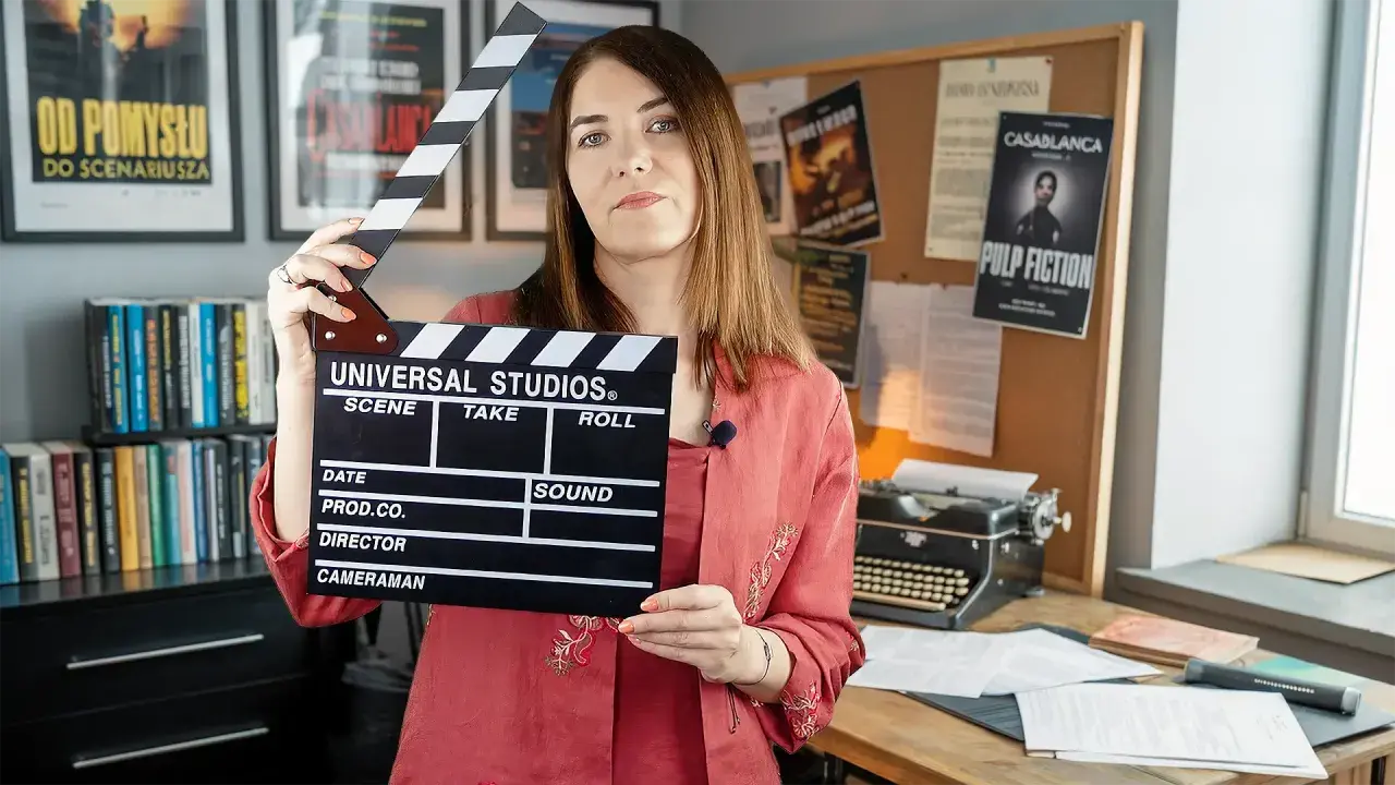 Kobieta trzyma klaps filmowy, gotowa do rozpoczęcia zajęć. W tle plakaty filmowe i maszyna do pisania, tworząc atmosferę pracy nad scenariuszem.