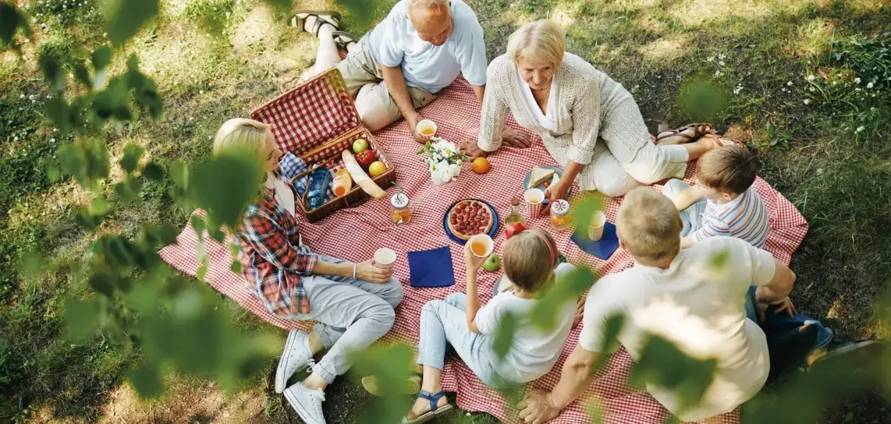 Rodzina cieszy się piknikiem na trawie. Dzień przyjaciela to idealny czas na takie spotkania.