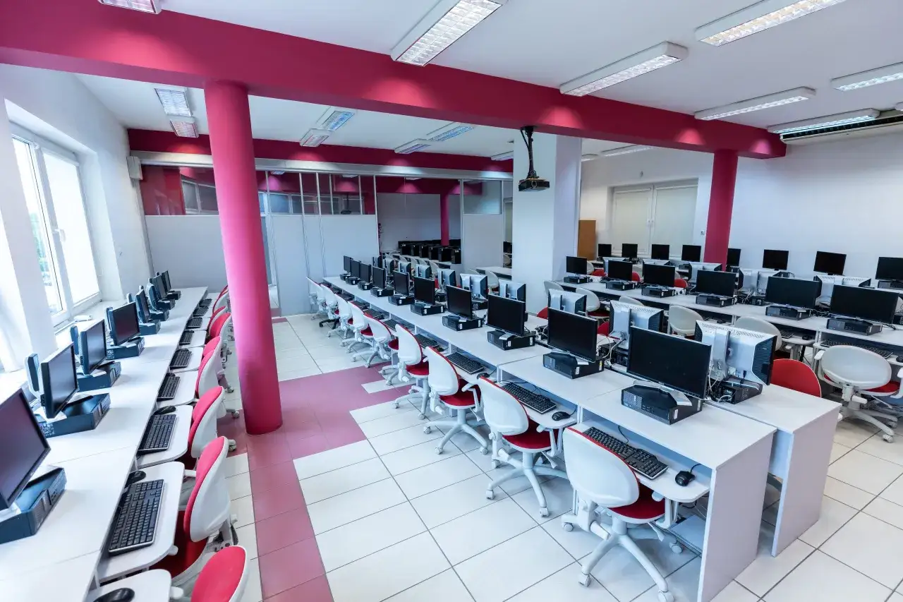 Rzędy komputerów w sali lekcyjnej, idealne do nauki i zdobywania wiedzy, np. na studiach podyplomowych.