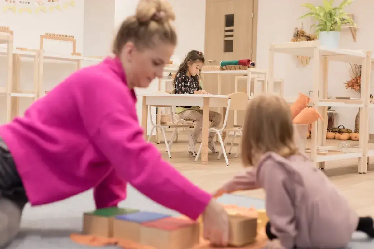 Nauczycielka wspiera dzieci w nauce metodą Montessori, rozwijając ich ciekawość i samodzielność.
