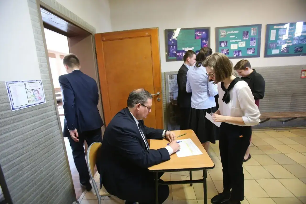 Uczniowie czekają na maturę ustną polski. Nauczyciel sprawdza dokumenty.