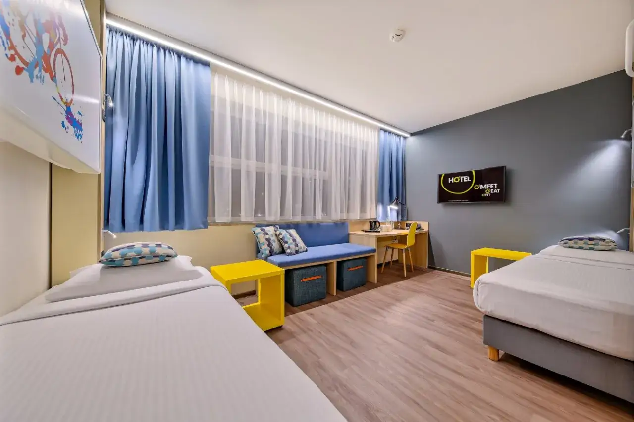 Pokój hotelowy z dwoma łóżkami, kanapą, biurkiem i telewizorem. To miejsce, gdzie można odpocząć, co to internat.