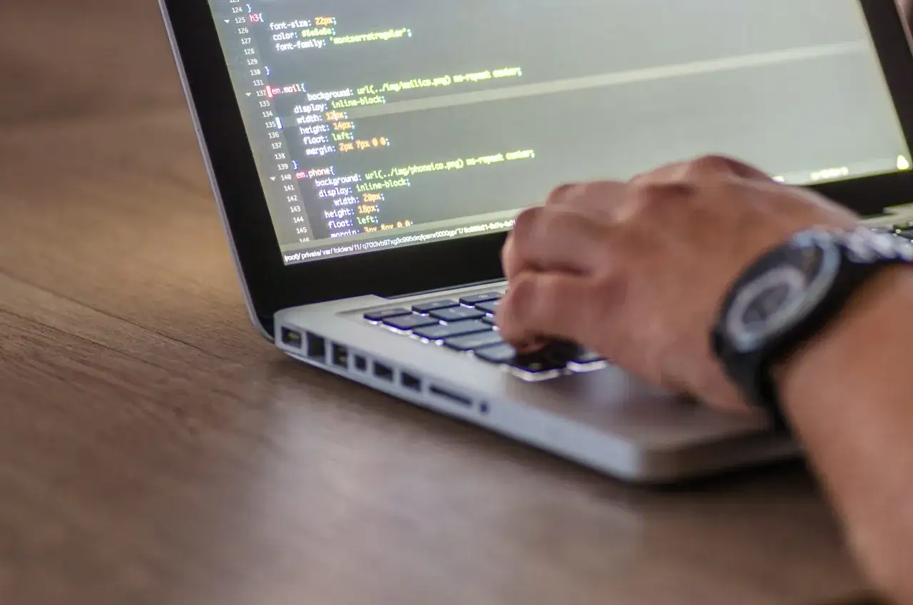 Osoba programująca na laptopie z widocznym kodem