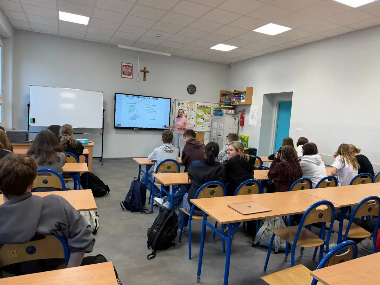 Nauczycielka tłumaczy uczniom, czy doradztwo zawodowe jest obowiązkowe. Sala lekcyjna pełna młodych ludzi.