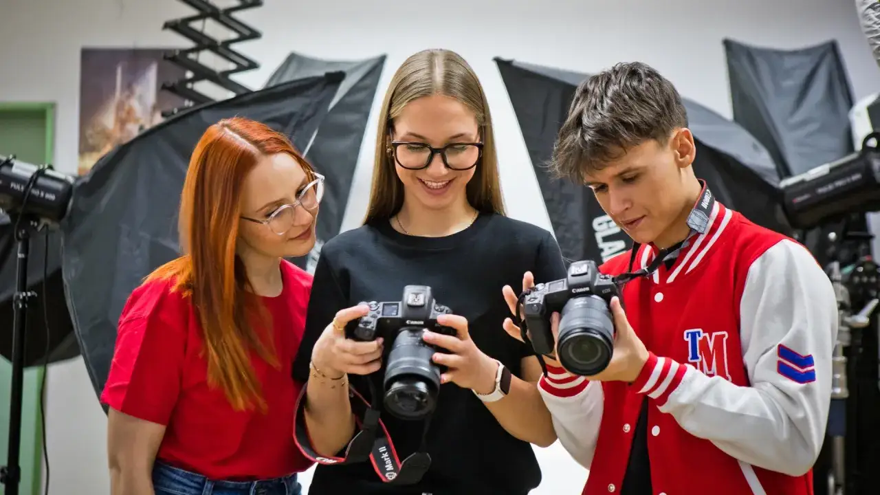 Trójka młodych ludzi, przyszłych specjalistów od technik fotografii i multimediów, analizuje sprzęt w studiu.