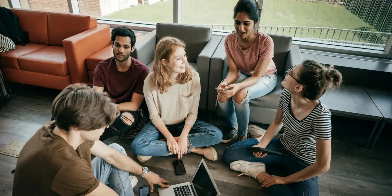 Grupa studentów dyskutuje o projektach, przygotowując się do matury międzynarodowej.